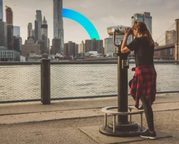 A woman observing the city through binoculars on the waterfront